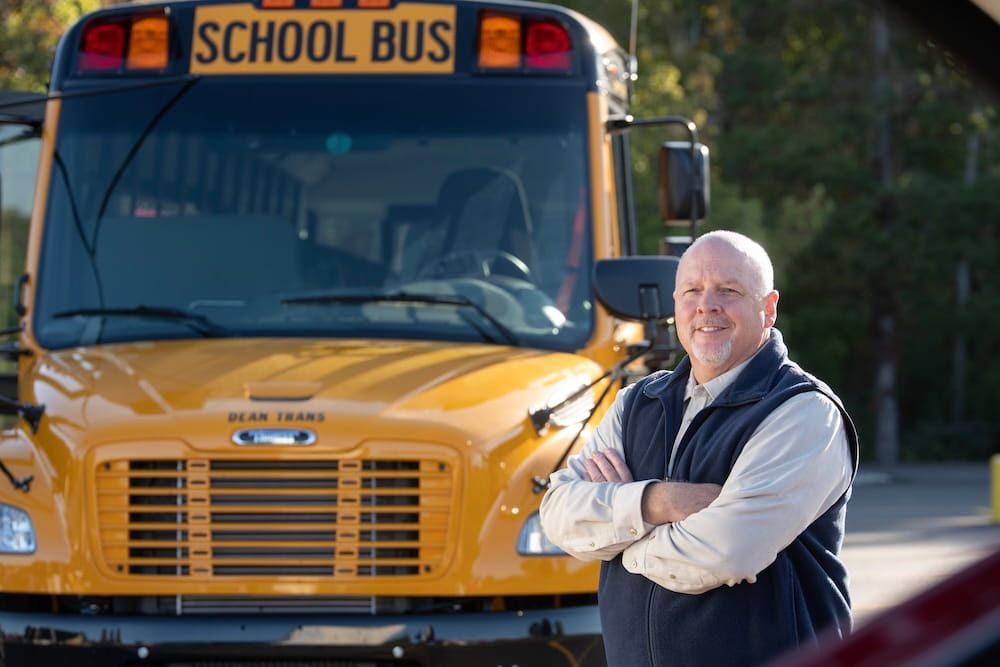 bus driver posing in front of a bus
