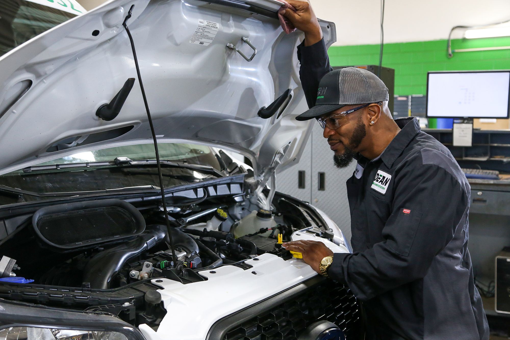 technician looking under the hood of a vehicle